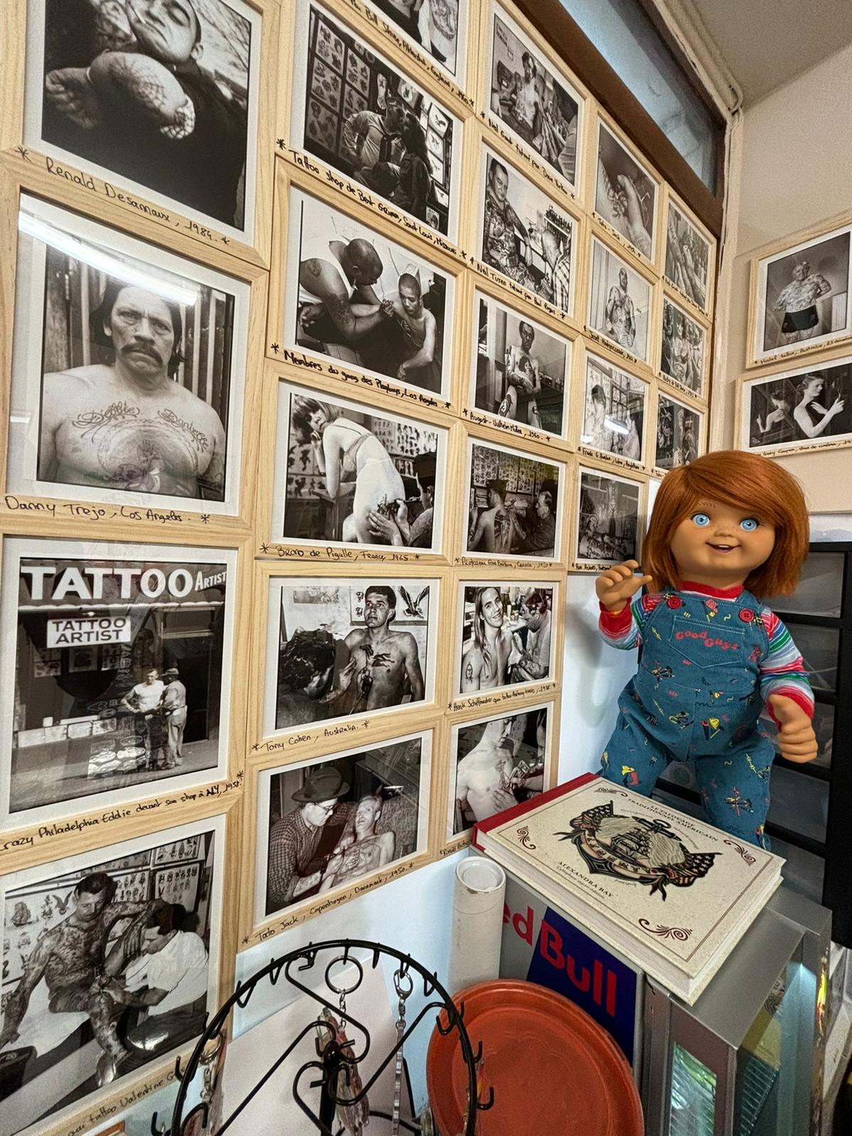 photo interieur du salon de tatouage des photos accrochés au mur et une poupée de Chuky